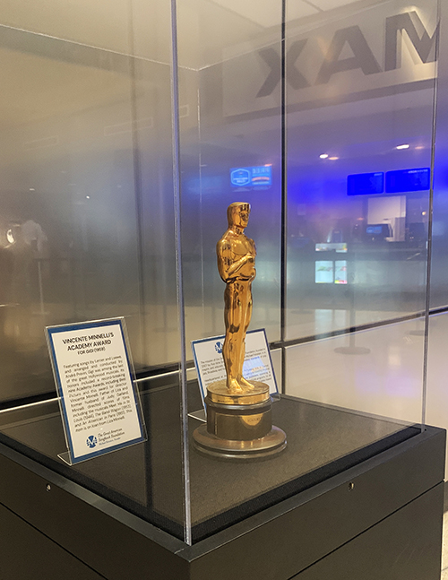 A gold Academy Award statuette sits in a plexiglass display case in the IMAX Theater lobby.