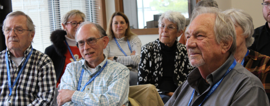 A group of elderly white people look at a presenter.