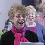 A participant of Perfect Harmony smiles and sings.