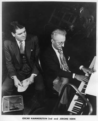 Oscar Hammerstein II observes as Jerome Kern plays the piano.