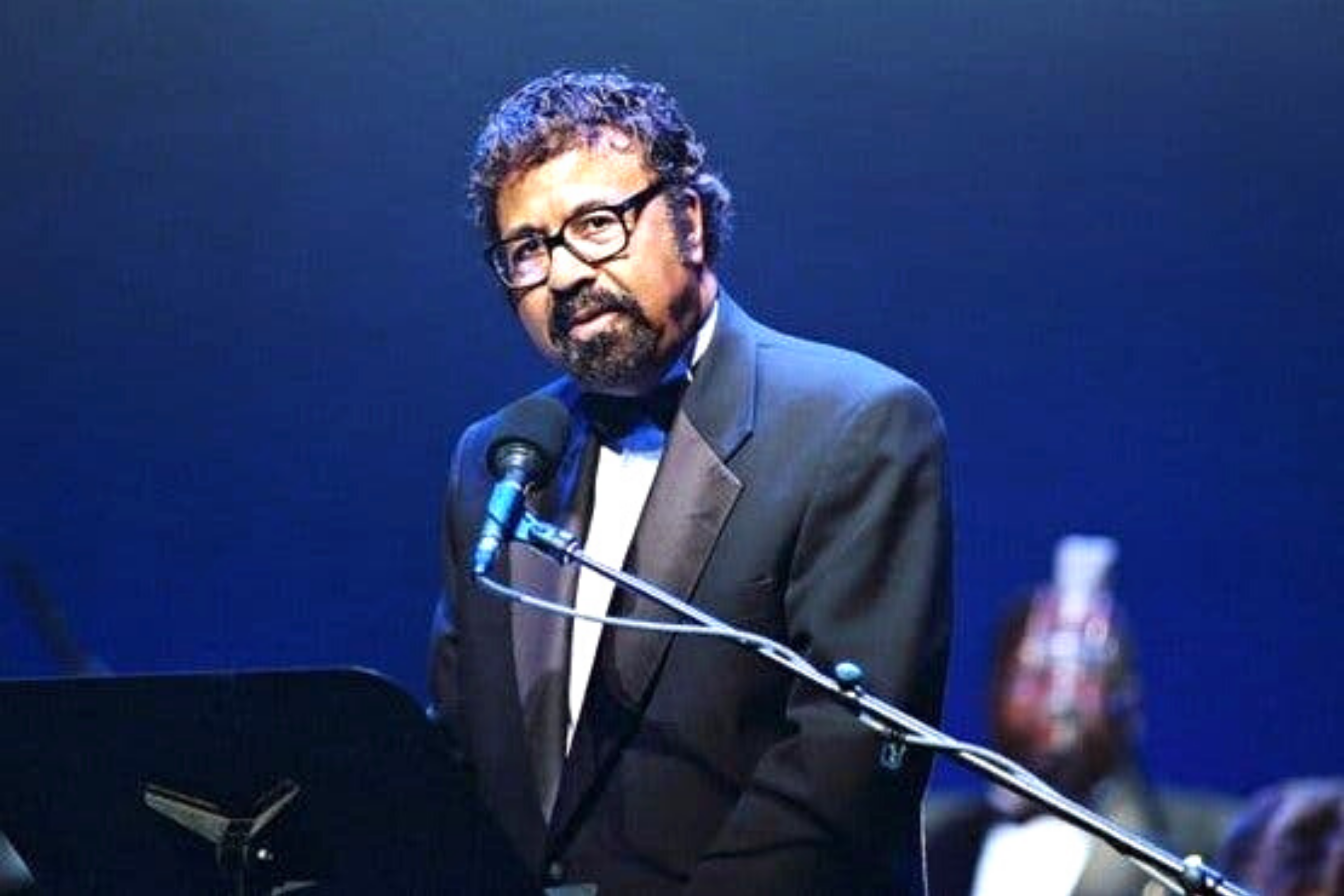 David Baker performs for an audience and stares into the crowd.