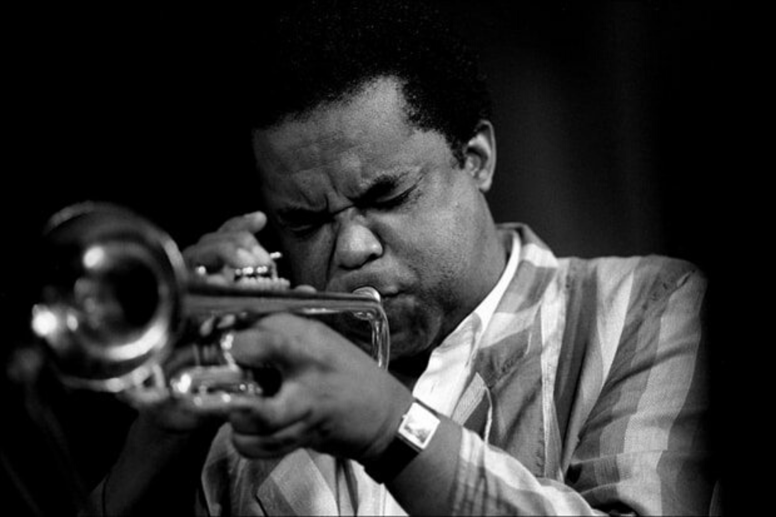 Freddie Hubbard plays his trumpet with concentration on his face.