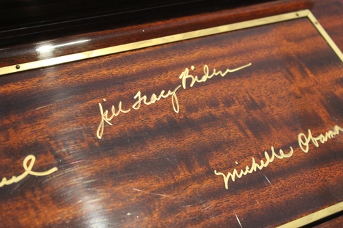 Jill Biden's signature in gold above Michelle Obama's signature.