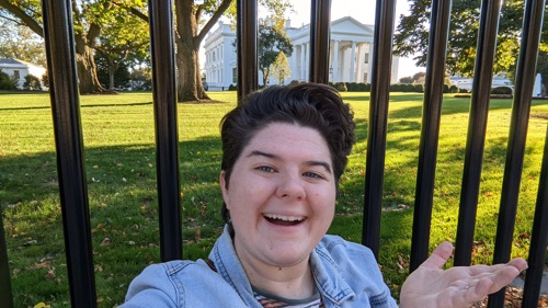 Chelsea gestures toward the White House and smiles.