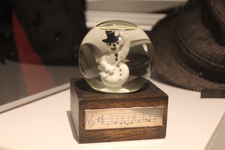 A snowglobe with a waving snowman. The opening notes to "White Christmas" are on a silver plaque.