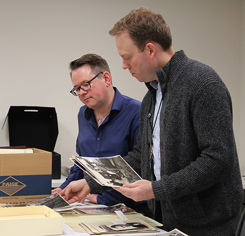 Two men look through files of photographs