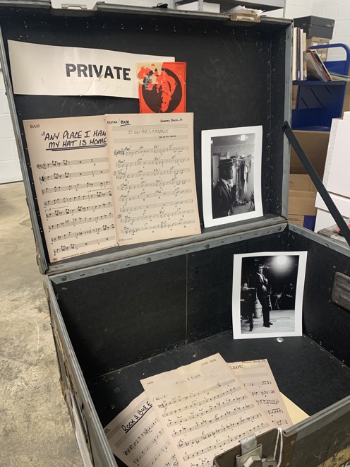 Inside of a Sammy Davis Jr. traveling trunk. Private is written in large letters with a red sticker of Sammy. Inside the trunk is sheet music for "Any Place I Hang My Hat is Home" and photos of Sammy on stage and in his dressing room.