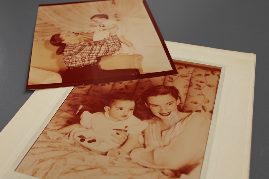 Two sepia images of Judy Garland a Liza Minnelli as a baby. Judy holds Liza in the air and smiles and Judy and Liza look to the right.