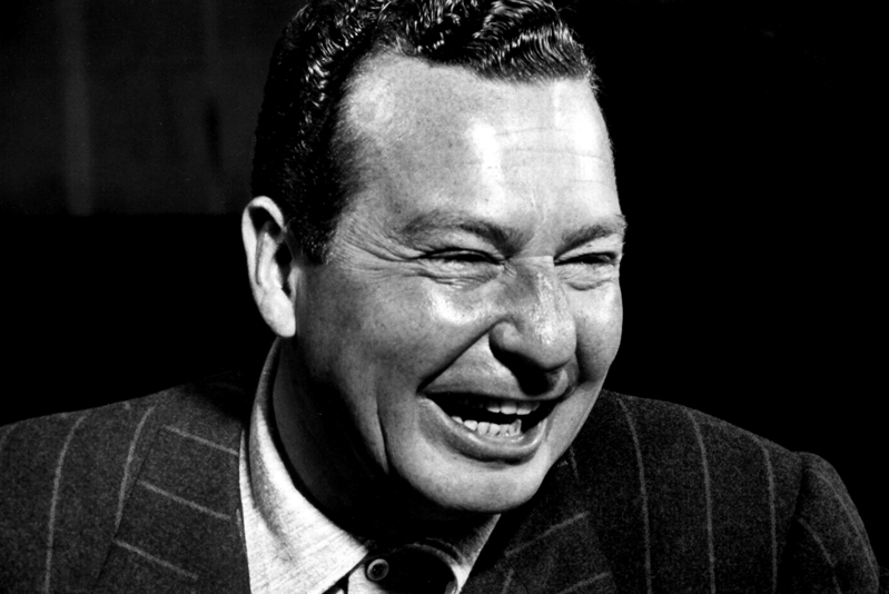 Phil Harris smiles in a pin striped suit.